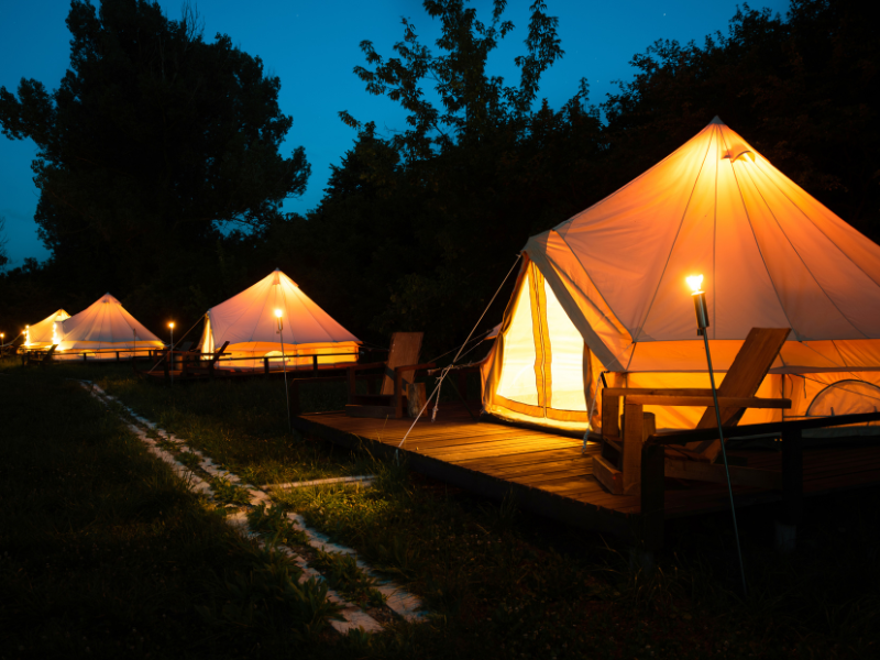travel business ideas - lit up glamping tents at campsite