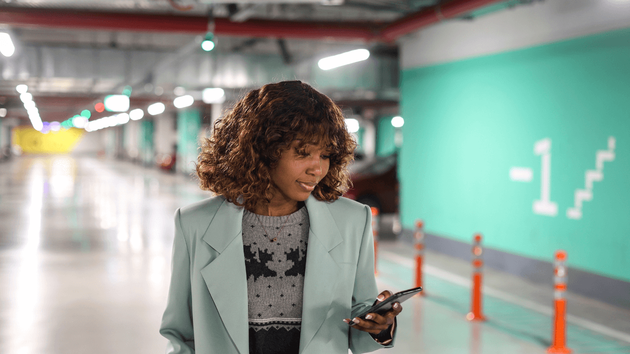 woman tapping her phone for a parking app in a parking lot